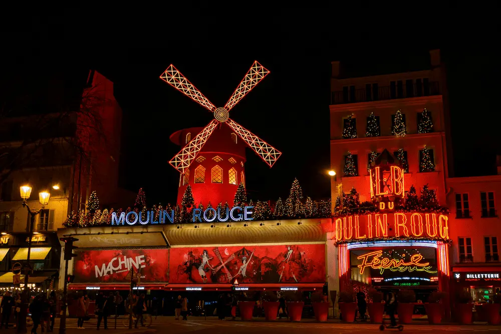 Fachada iluminada e moinho vermelho do Moulin Rouge em Paris
